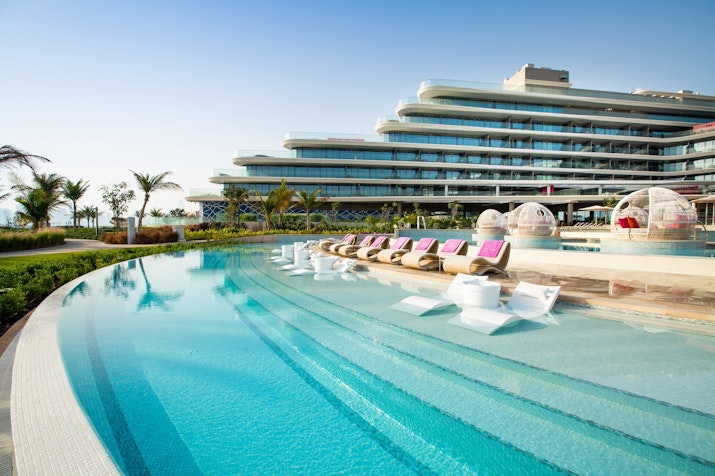 Luxurious pool area with lounge chairs and modern hotel building in the background
