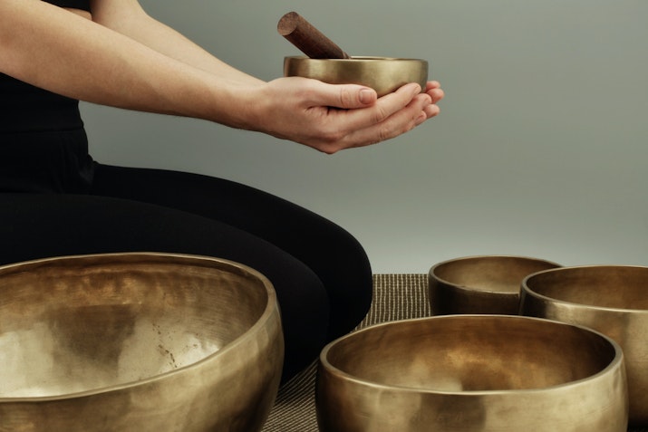 Privilee from Day to Night in Dubai Person holding a singing bowl with others placed nearby, used for sound therapy
