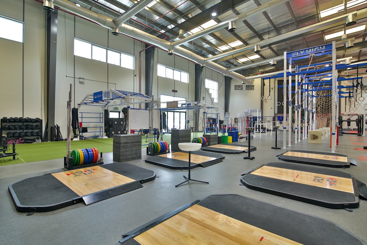 A well-equipped indoor gym with various weightlifting platforms, exercise equipment, and training areas.