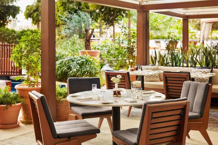 Alba Terrace at The Abu Dhabi EDITION Intimate garden dining surrounded by lush greenery for a tranquil experience.
