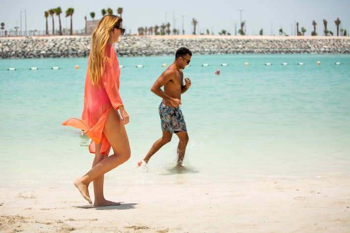 Couple enjoying a beach day by the turquoise sea.