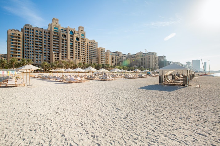 Fairmont The Palm Beachfront resort with lounge chairs and luxury buildings in the background