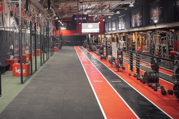 Gym with weightlifting equipment and a track area for training.