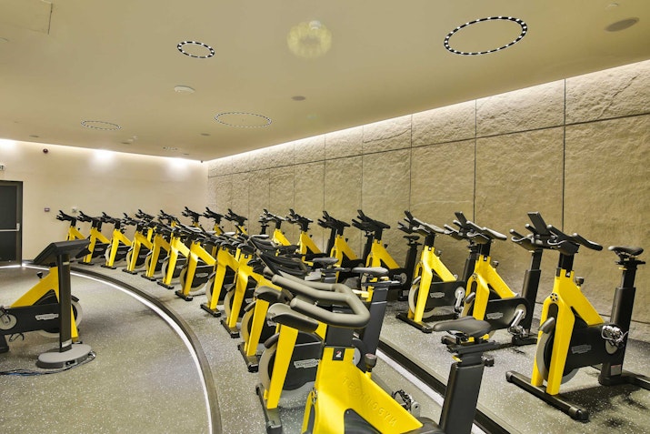 Empty indoor cycling room with rows of yellow stationary bikes