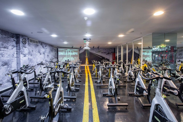 Indoor cycling studio with road-themed decor and rows of stationary bikes.