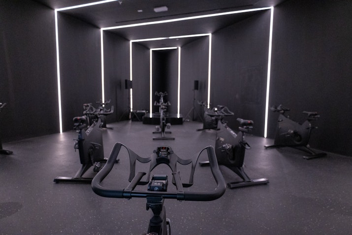 Dark indoor cycling studio with neon lighting and stationary bikes.