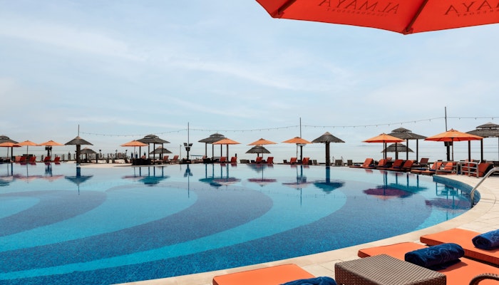 Al Maya Island & Resort Infinity pool with orange umbrellas and lounge chairs.