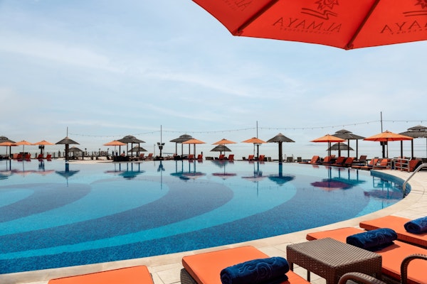 Infinity pool with orange umbrellas and lounge chairs.