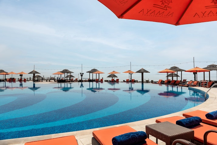 Infinity pool with orange umbrellas and lounge chairs.