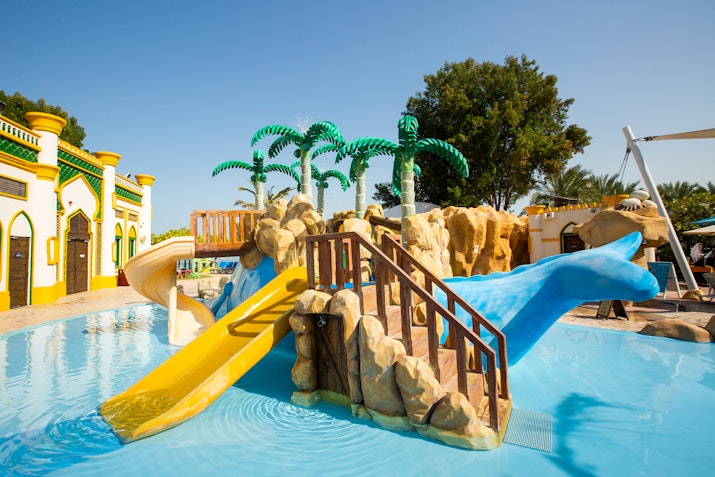Children's pool area with slides and decorative palm trees