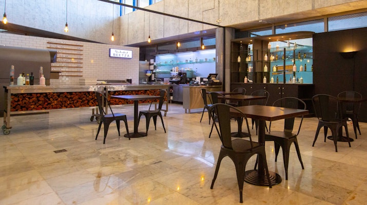 Modern cafe with industrial-style decor and metal chairs.