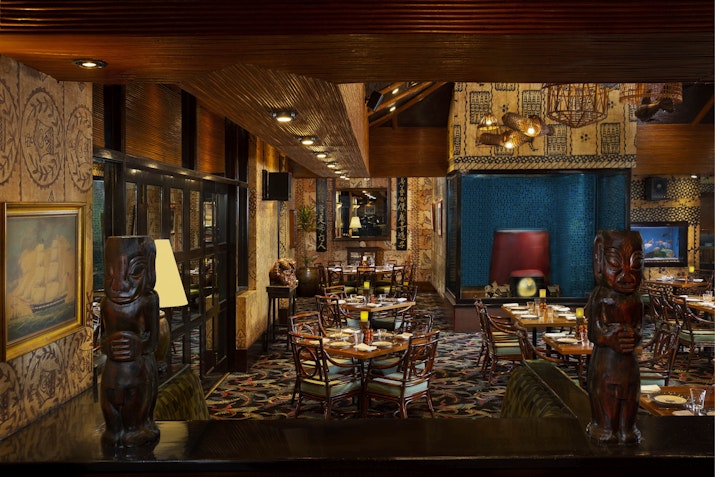 Vintage-themed restaurant with Polynesian decor and intricate wood carvings.