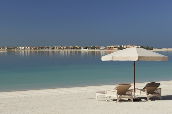Dubai during Ramadan Two lounge chairs under an umbrella on a sandy beach