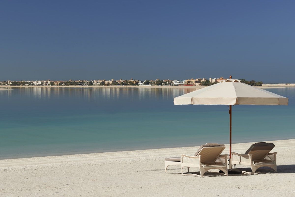Dubai during Ramadan Two lounge chairs under an umbrella on a sandy beach