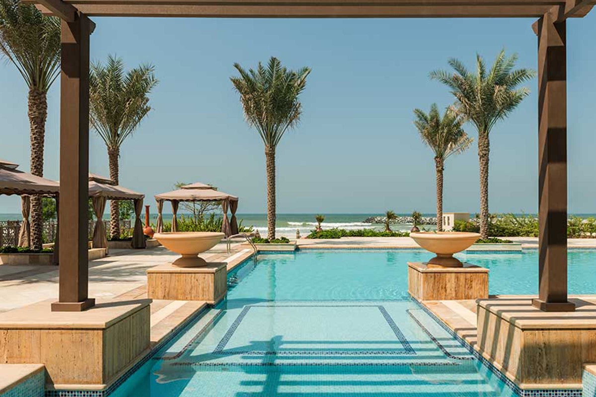 Ajman Saray Elegant courtyard with a water feature and palm trees overlooking the ocean