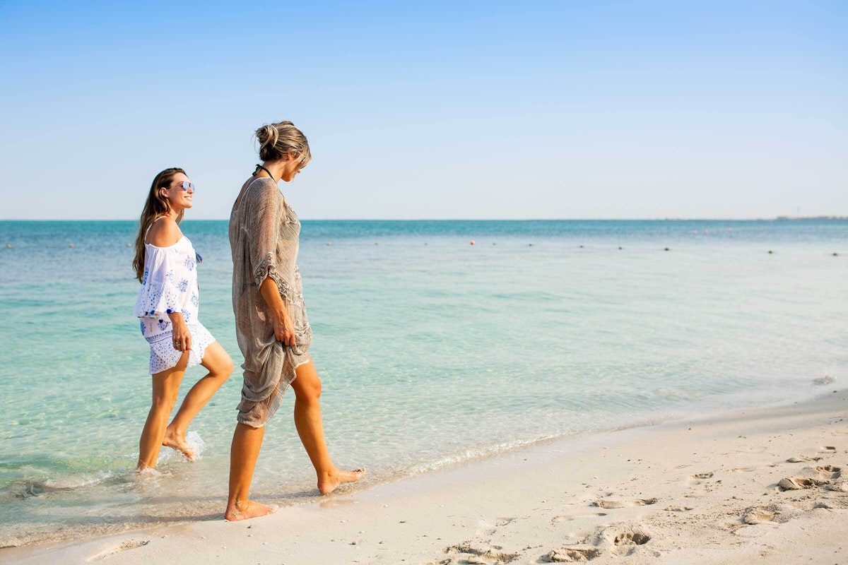Couple walking along a sandy beach by the clear blue sea