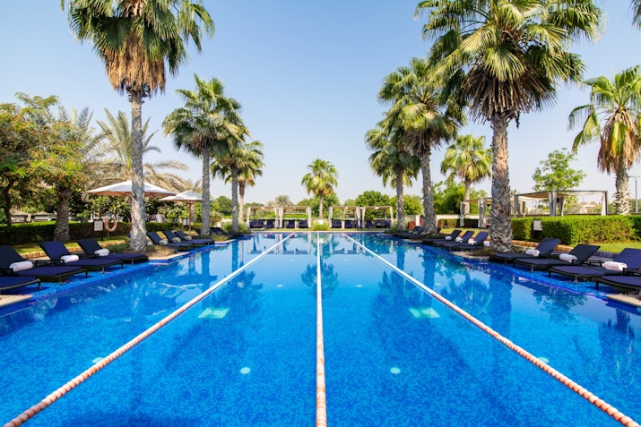 Lap pool at VOGO Abu Dhabi Golf Resort & Spa Long pool with lap lanes, lined with palm trees and sun loungers.