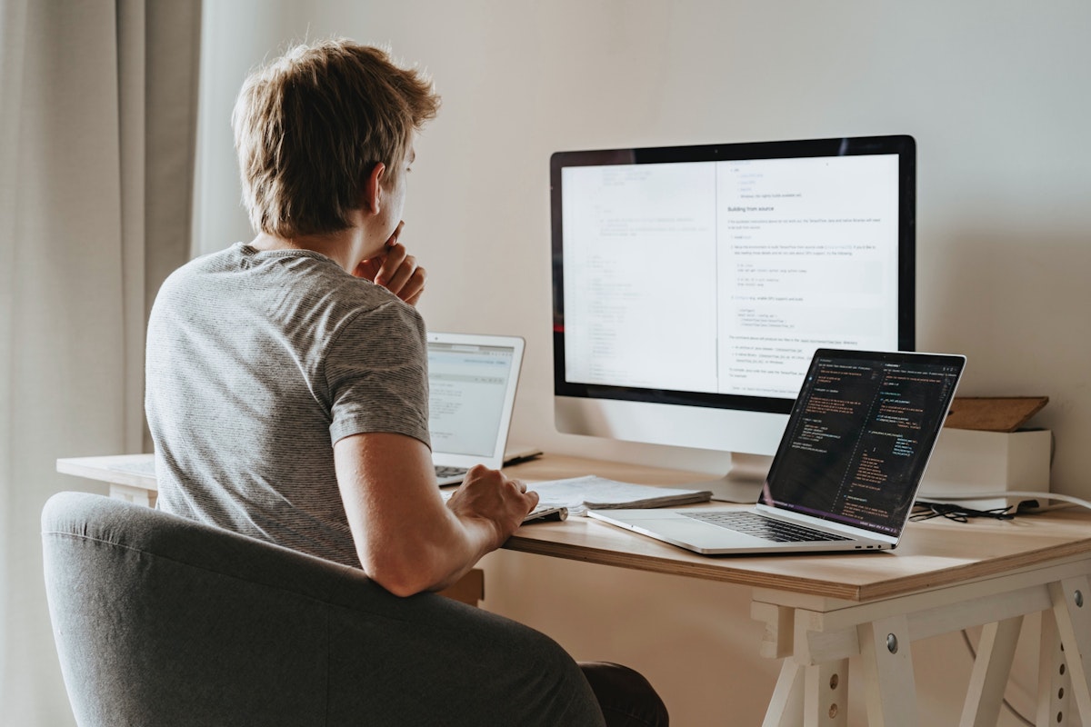 Person working with multiple screens in a home office setup.