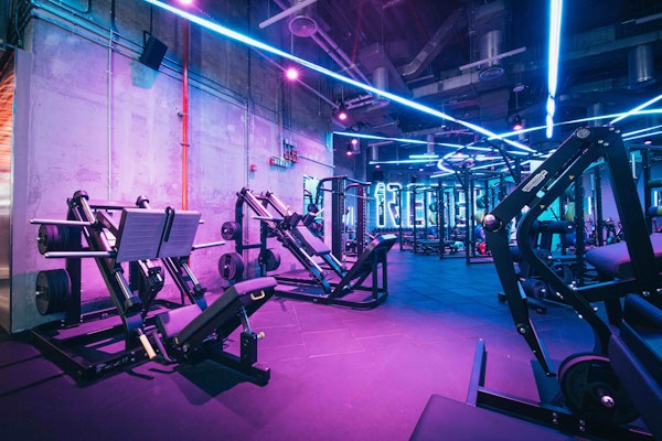 Modern fitness machines in neon-lit, industrial-style gym.