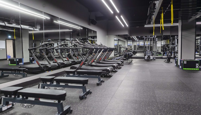 700 Padel & Fitness Hub Modern gym interior featuring lined-up benches and treadmills, with a sleek and spacious layout.