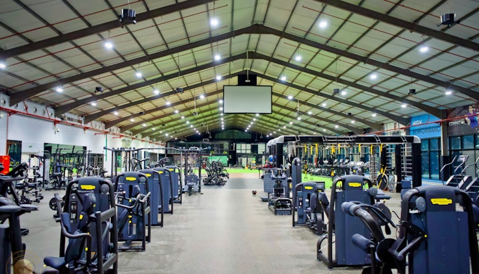 AB Fitness in Dubai Large fitness center featuring rows of exercise machines, open training areas, and a high ceiling with bright lighting for an airy and well-equipped workout environment.