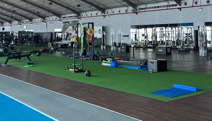 AB Fitness in Dubai Large gym featuring a turf area for functional exercises, surrounded by various workout equipment and open spaces under a high ceiling.
