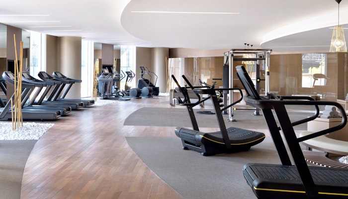 Address Sky View Spacious modern gym with treadmills, ellipticals, and other fitness equipment arranged along a curved wooden floor path