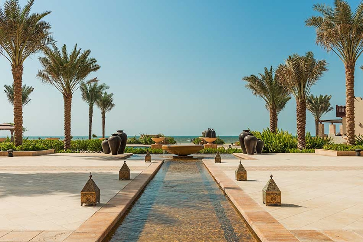 Ajman Saray Elegant courtyard with a water feature and palm trees overlooking the ocean