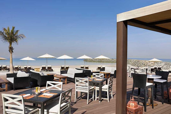 Outdoor beachside dining area with tables and umbrellas