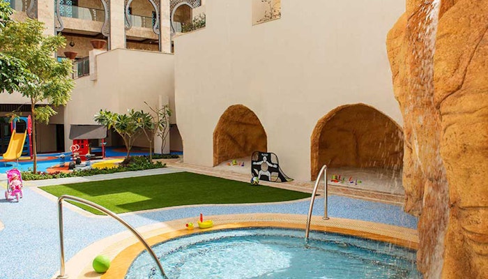 Ajman Saray Children's play area with a small pool and cave-like structures.