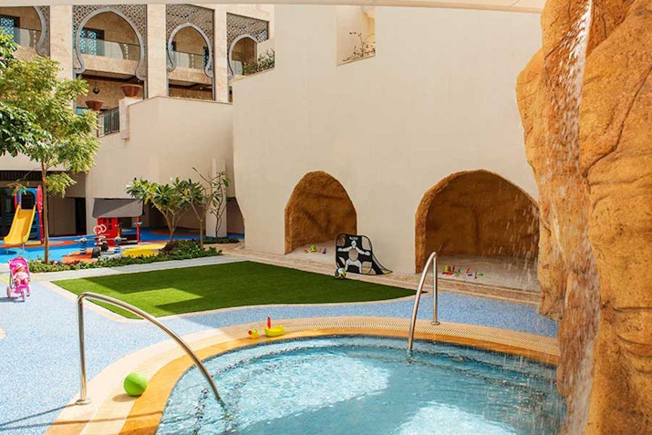 Children's play area with a small pool and cave-like structures.