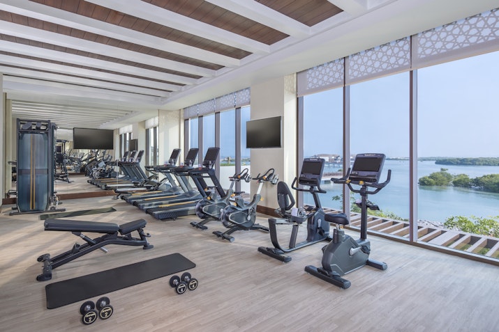 Bright gym with fitness equipment and large windows overlooking a scenic view.