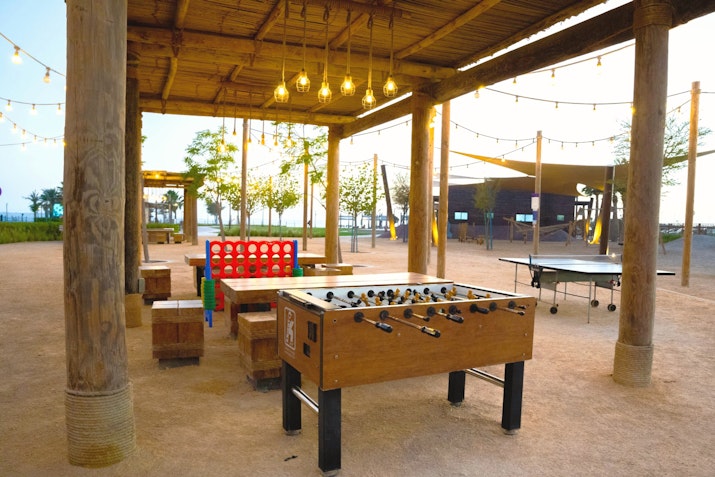 Outdoor game area with foosball table, Connect Four, and string lights.