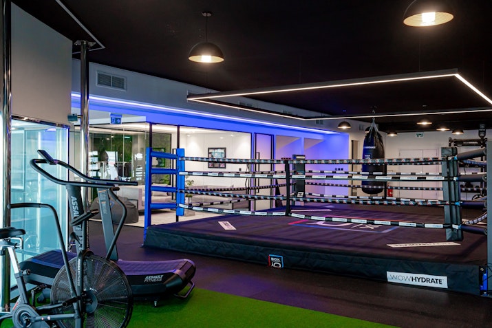 BOXiQ Modern boxing gym with a central boxing ring, workout equipment, and ambient lighting