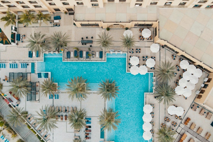 Aerial view of a swimming pool surrounded by lounge chairs and palm trees.
