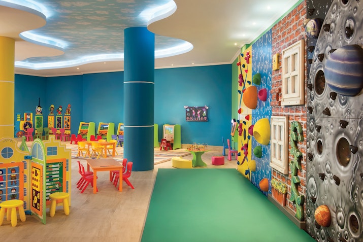 Colorful children's playroom with toys, games, and a space-themed wall.