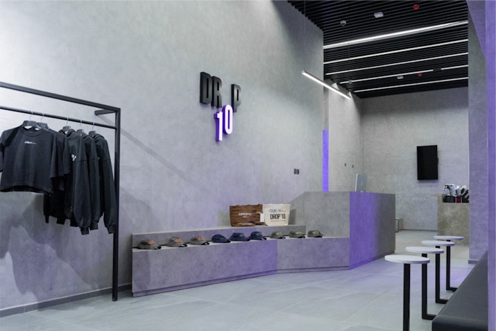 Minimalist gym reception area with sleek, clean aesthetic, featuring grey walls and the Drop10 logo