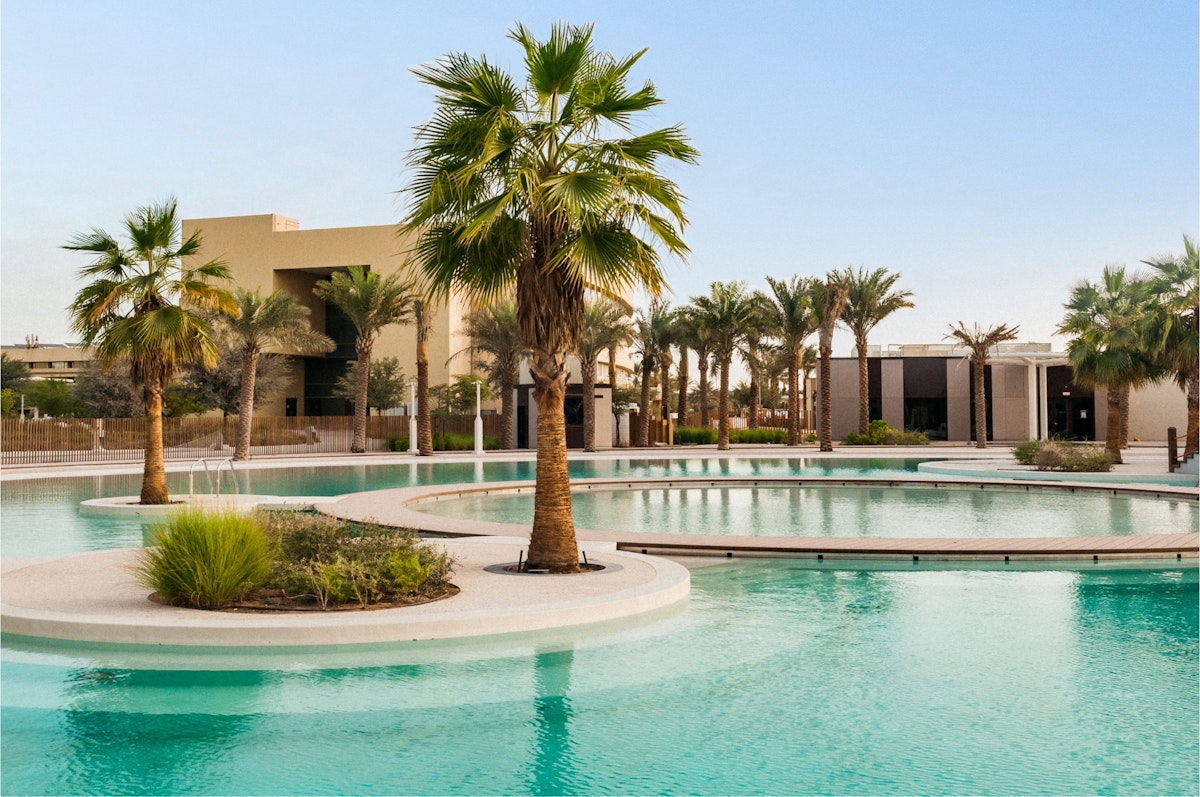 Outdoor pool with palm trees and resort buildings.