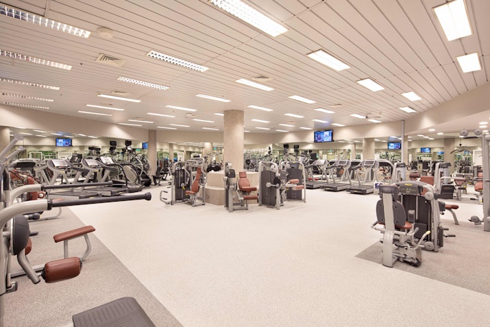 Large, well-equipped gym space with various exercise machines and ample lighting.