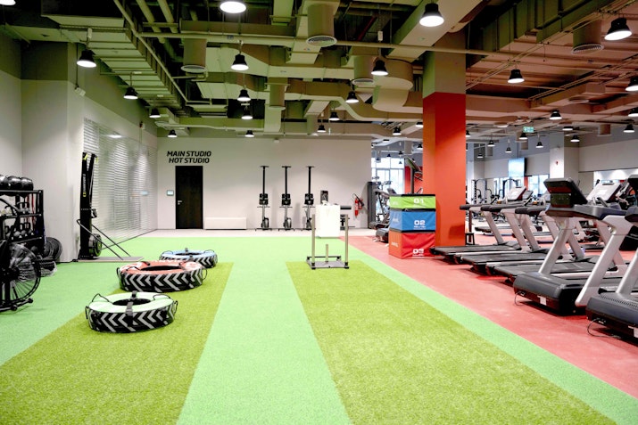 Functional training area featuring large tires, turf, sled push area, and cardio machines.