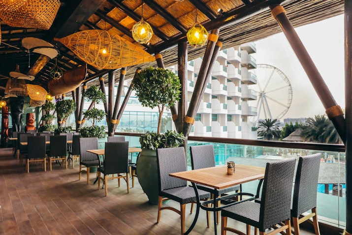 Outdoor restaurant seating with a view of a Ferris wheel