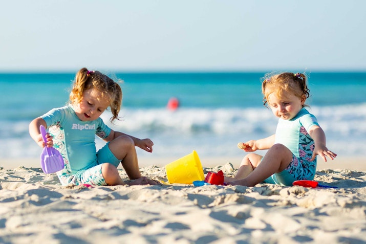 Two young girls playing with beach toys on the sand