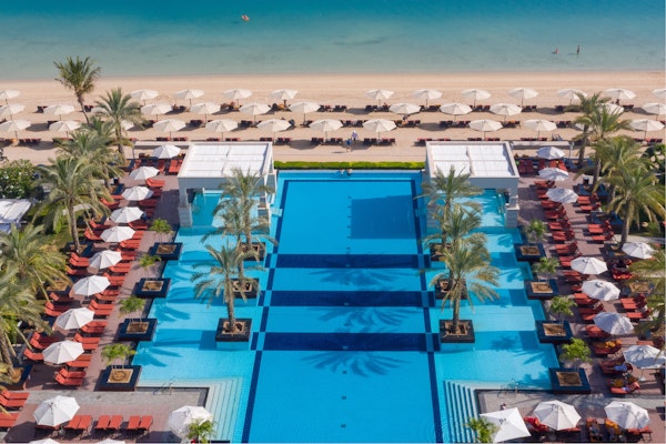 Aerial view of luxury resort pool with surrounding beach loungers and umbrellas.