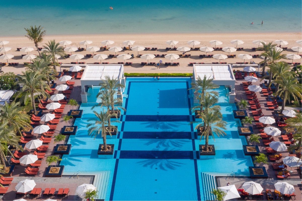 Aerial view of luxury resort pool with surrounding beach loungers and umbrellas.