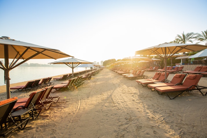 Beach loungers and umbrellas lined up along the sandy shore at sunrise