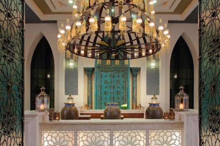Luxurious lobby area with intricate chandelier, ornate wall decor, and traditional lanterns.