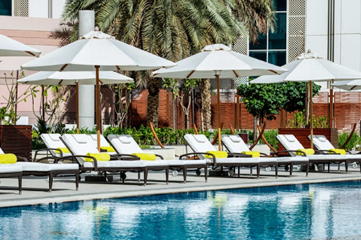 Poolside lounge chairs with white umbrellas.