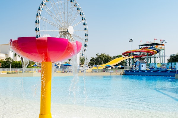 water play area with slides, splash features, and a Ferris wheel in the background.