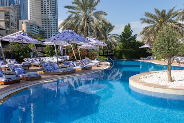 Poolside area with patterned loungers, umbrellas, and palm trees.