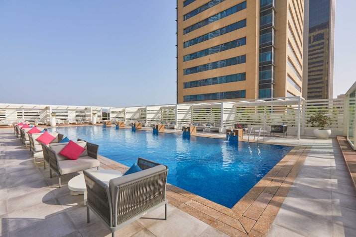 Media One Hotel Rooftop pool area with seating and high-rise buildings in the background